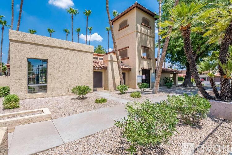 A building with a tan facade is surrounded by palm trees.