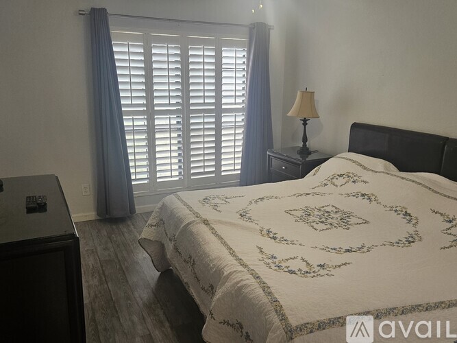 A bedroom with a large bed and a nightstand with a lamp.