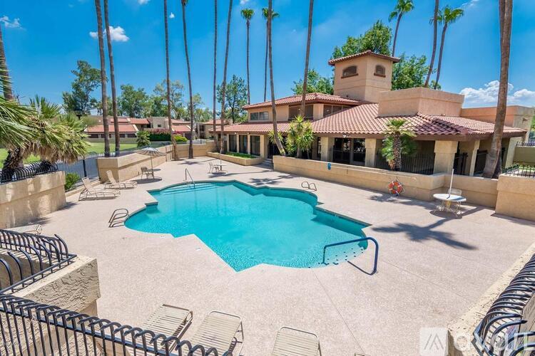 A pool surrounded by palm trees and a building in the background.