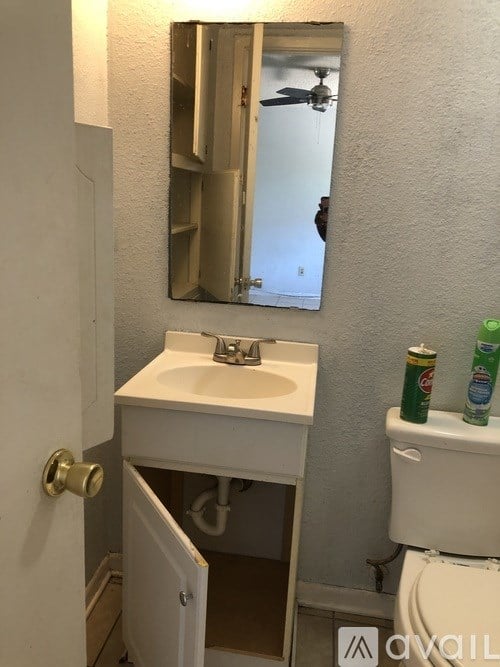 A bathroom with a sink, toilet, and mirror.