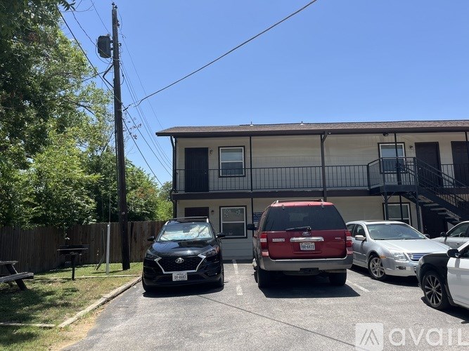 A black car is parked in front of a two-story apartment building.