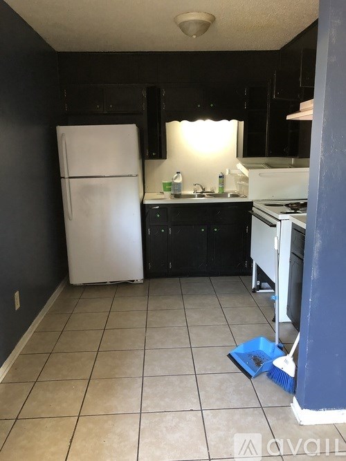 A kitchen with black cabinets and a white refrigerator.