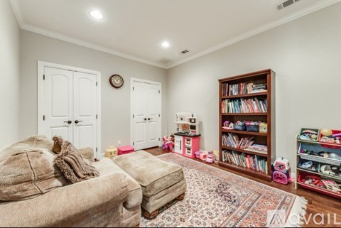 A living room with a couch, a rug, and a bookshelf filled with books.
