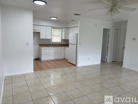 A kitchen with white cabinets and a refrigerator is available for rent.