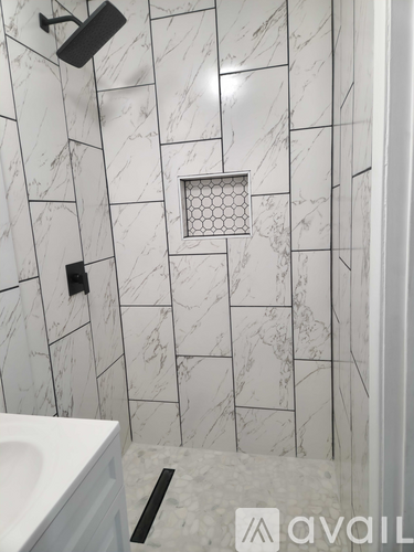 A bathroom with a white sink and a marble tile wall.
