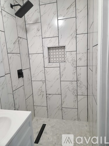 A bathroom with a white sink and a marble tile wall.
