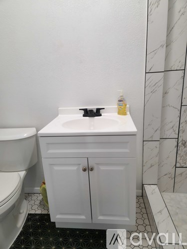 A white bathroom with a sink, toilet and a cabinet.
