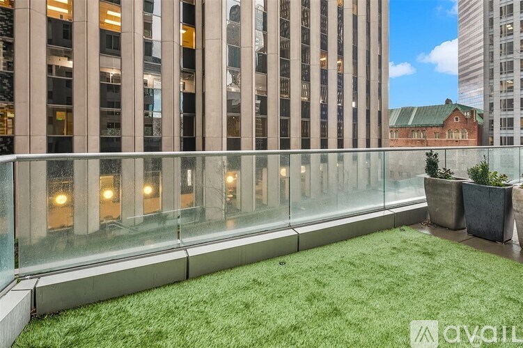 A glass balcony with a green lawn and potted plants.