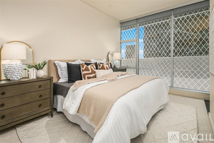 A bedroom with a large bed, a dresser, and a window with a metal grate.