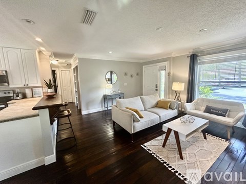 A well-lit living room with a white sofa and wooden floors.