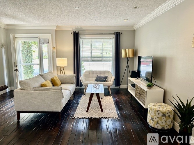 A living room with a white couch, a coffee table, and a television.