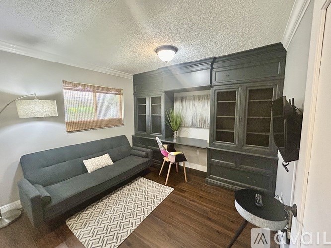 A living room with a grey couch and a wooden cabinet.
