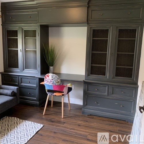 A room with a grey cabinet and a chair with a colorful blanket on it.