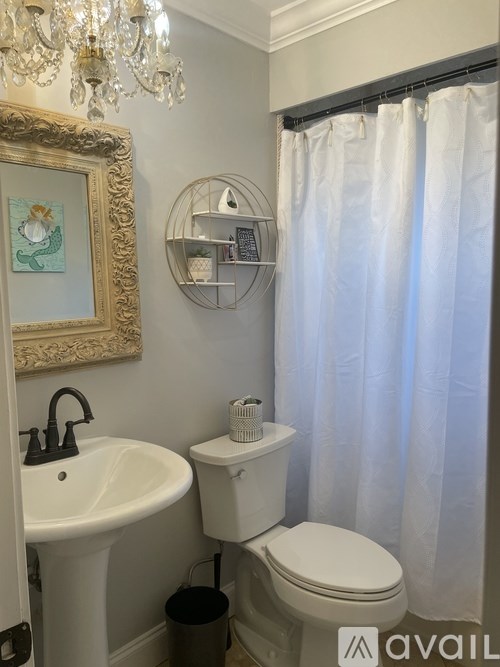 A bathroom with a white toilet, sink, and a chandelier.