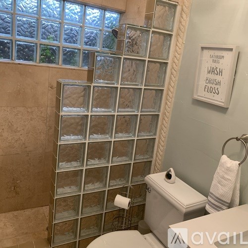 A bathroom with a toilet, a towel, and a sign that says "Bathroom Rules Wash Brush Floss".