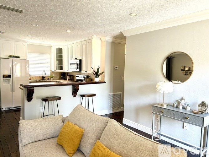 A modern kitchen with a bar area and a couch with yellow pillows.