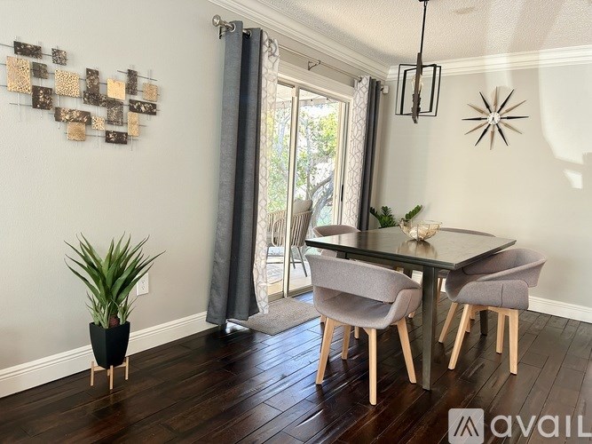 A dining room with a glass table and grey chairs.