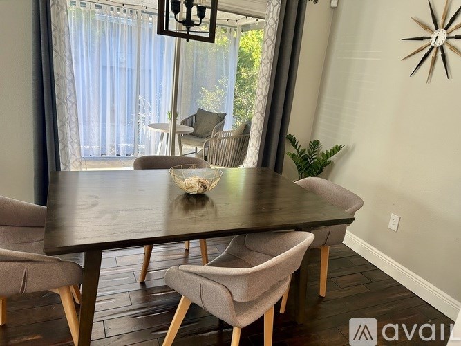 A dining table with chairs and a decorative wall clock.