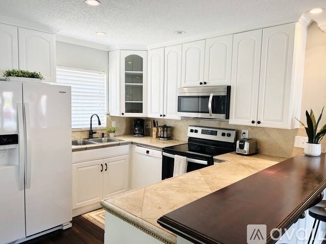 A kitchen with white cabinets and a wooden counter.