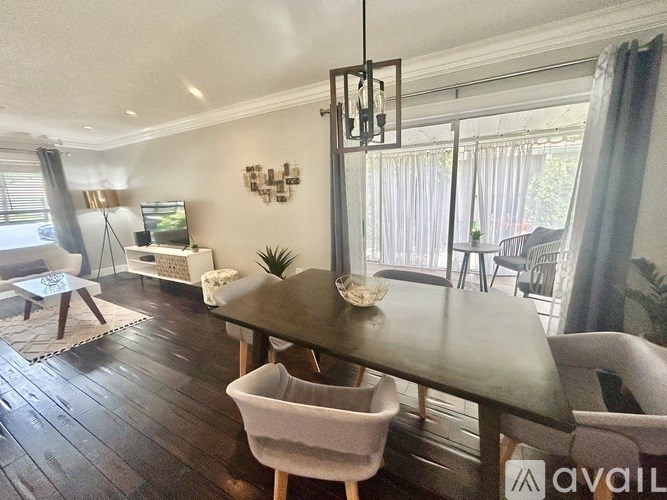 A modern dining room with a dark wood table and white chairs.