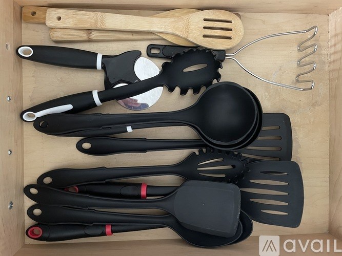 A set of kitchen utensils including spatulas and spoon rests in a wooden box.