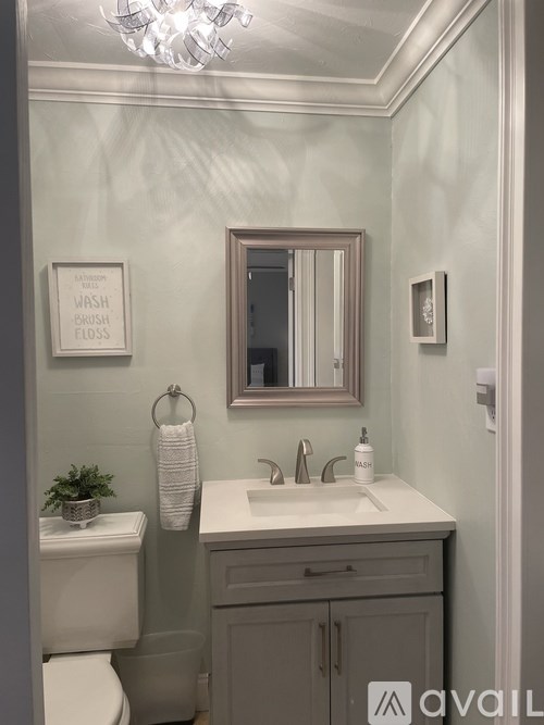 A bathroom with a white toilet, sink, and a mirror.