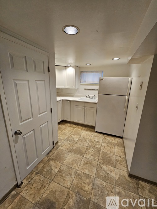 A kitchen with a white door and a white fridge.