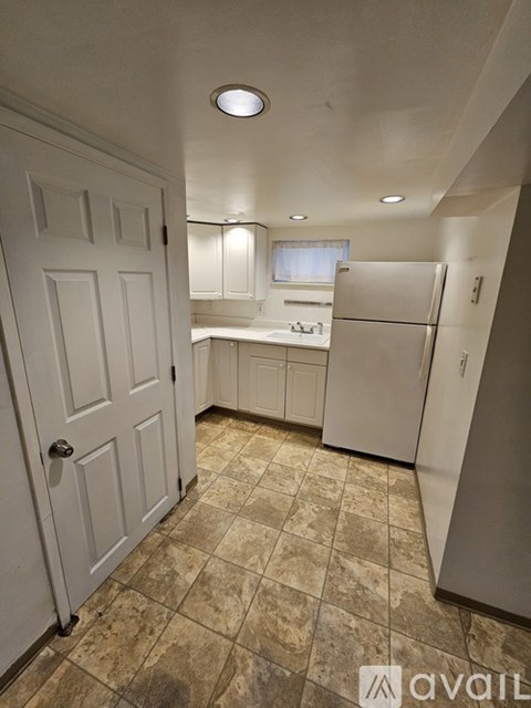 A kitchen with a white door and a white fridge.