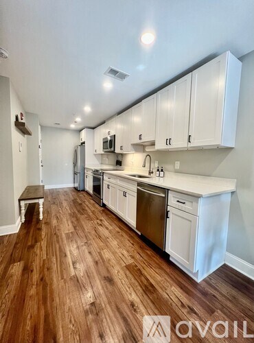 A kitchen with white cabinets and wooden floors.