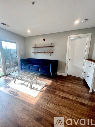 A living room with a blue couch and wooden floors.