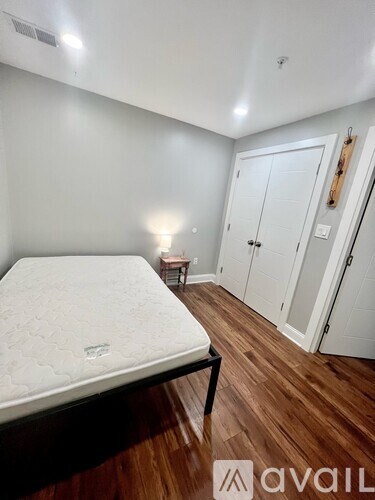 A bedroom with a bed, wooden floor, and a wall-mounted cabinet.