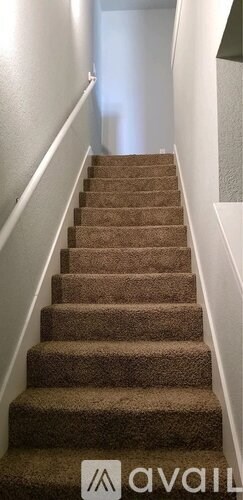 A staircase with a carpeted runner and white handrails.