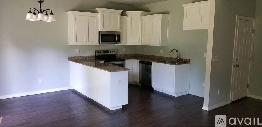 A kitchen with white cabinets and a granite countertop.