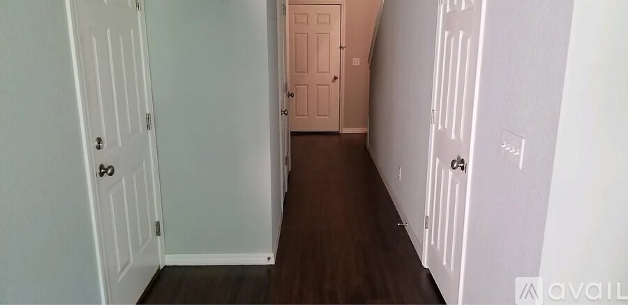 A hallway with white doors and a brown floor.