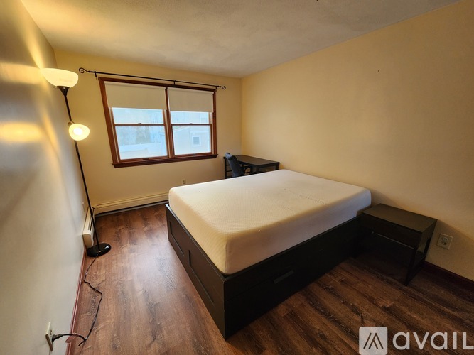 A bedroom with a bed, a window, and a lamp.