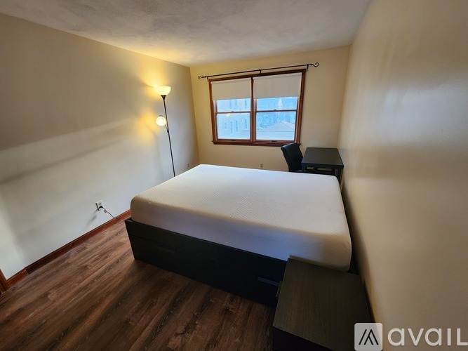 A bedroom with a bed, desk, and window.