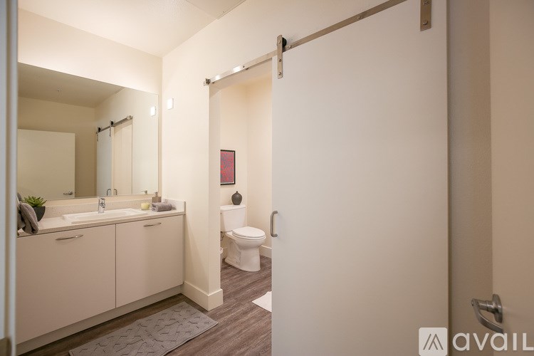 A bathroom with a toilet, sink, and mirror.