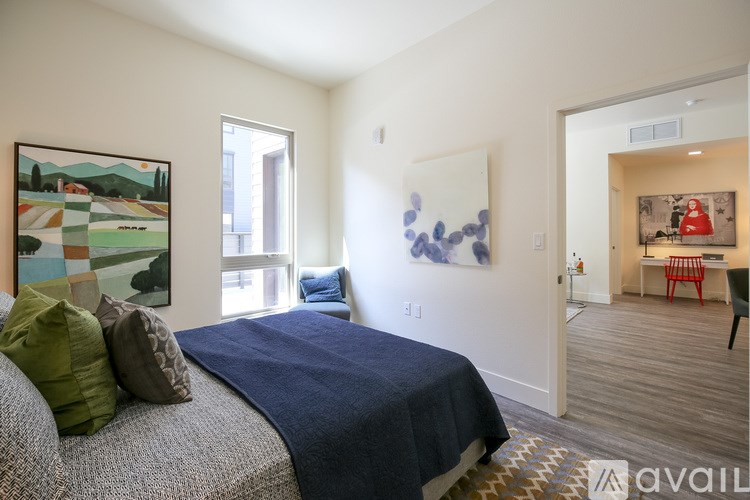 A bedroom with a bed, a chair, and a painting on the wall.