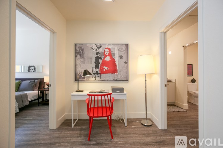 A room with a red chair and a painting on the wall.