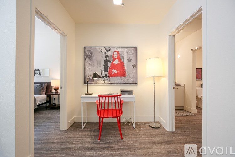 A room with a red chair and a painting on the wall.