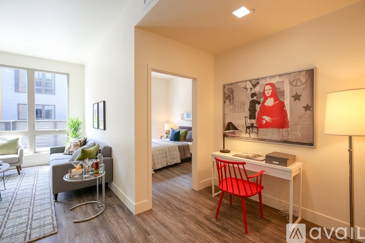 A room with a red chair and a painting of a woman in red.
