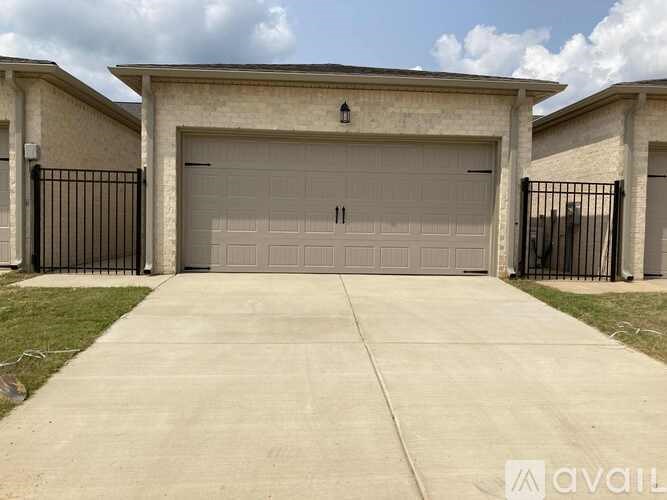 A two-car garage with a concrete driveway and black metal fence.