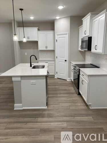 A kitchen with white cabinets and a wooden floor.