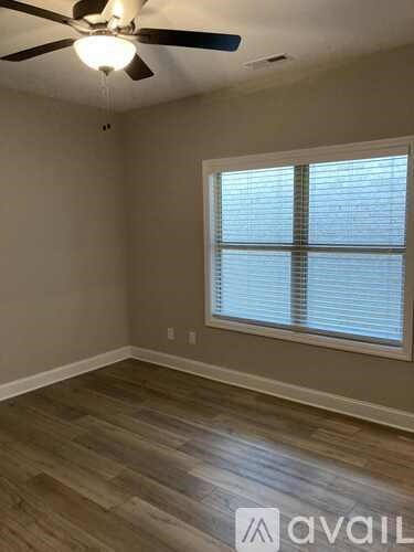 A room with a ceiling fan and a window with blinds.