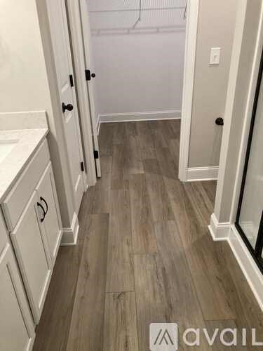 A hallway with wood flooring and white walls.