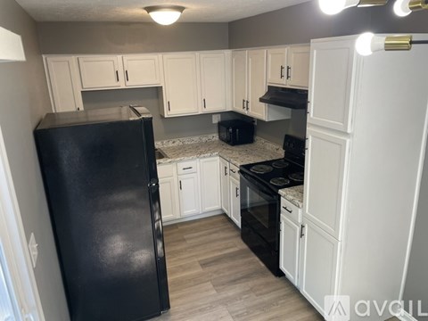 A kitchen with black appliances and white cabinets.