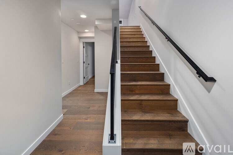 A staircase with wooden steps and a black handrail.