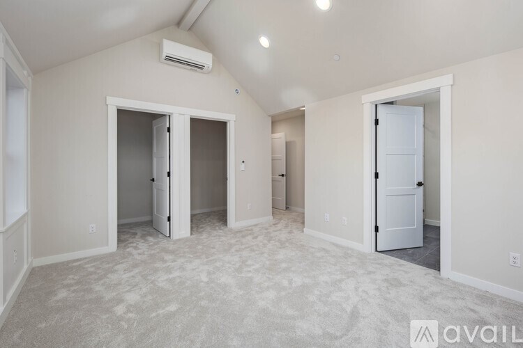 A spacious room with carpeted floor and two open doors.
