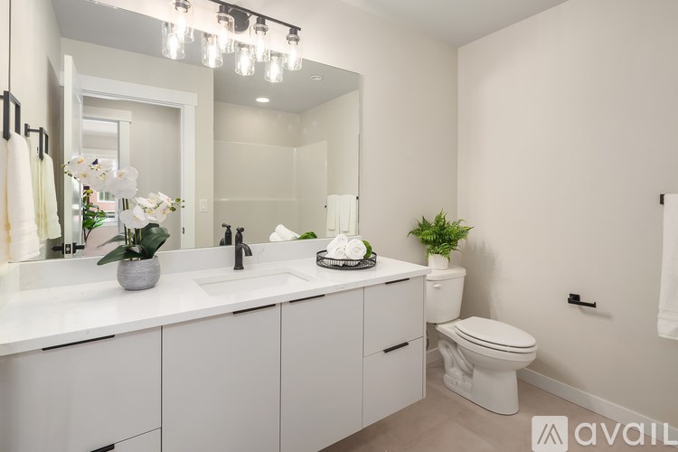 A bathroom with a white toilet, sink, and mirror.