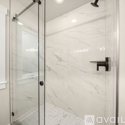 A white marble bathroom with a glass shower door.